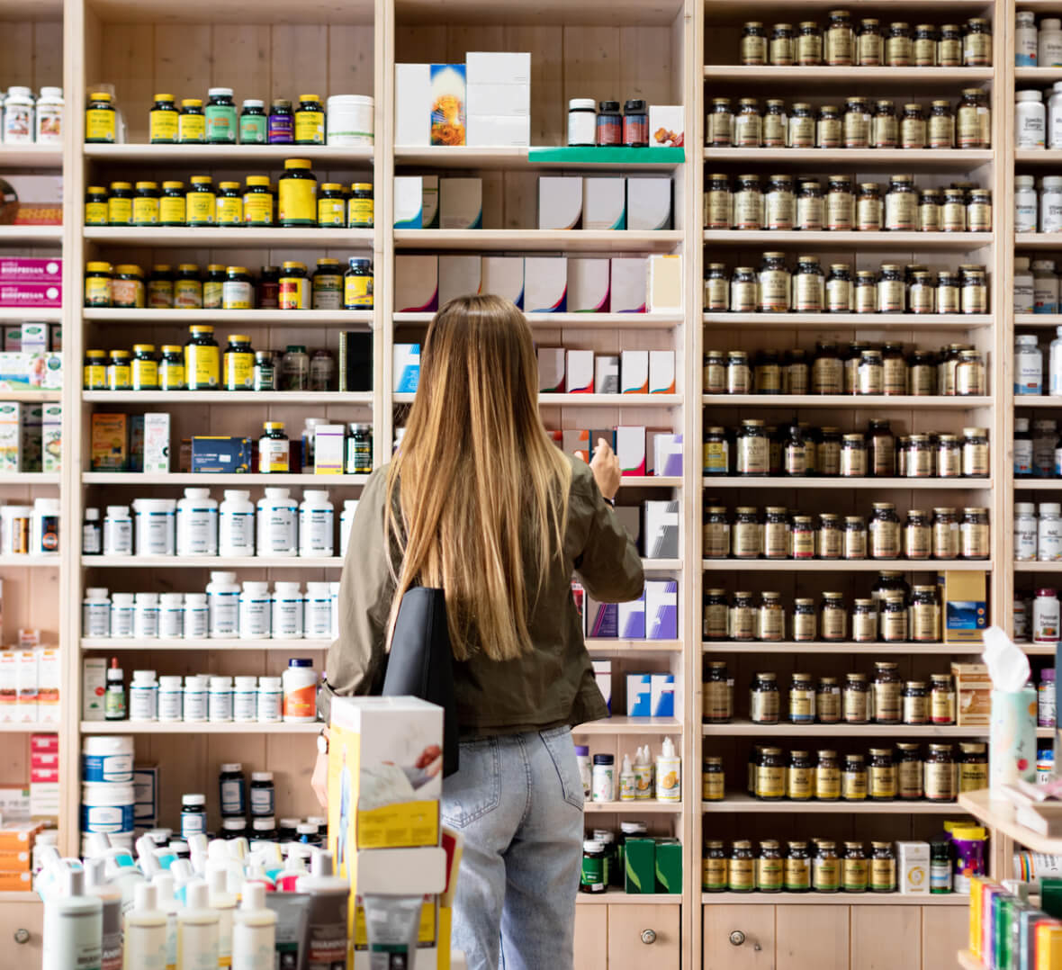 a brunette woman looking at shelves of suppliments